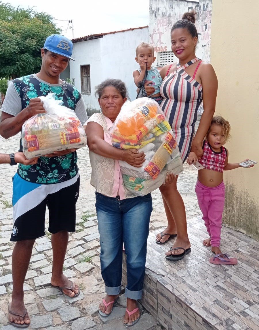 Adultos e crianças reunidos com cestas de alimentos